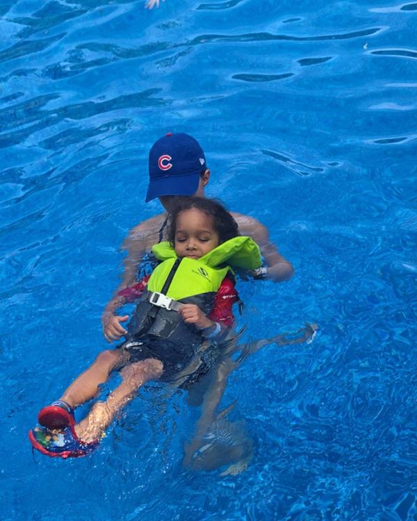 An instructor supporting a small child in a life jacket through a back float