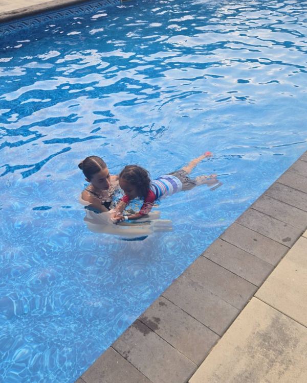 Annika steadying a kickboard as a young swimmer glides across the pool